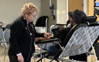 Nurse tending to woman donating blood.